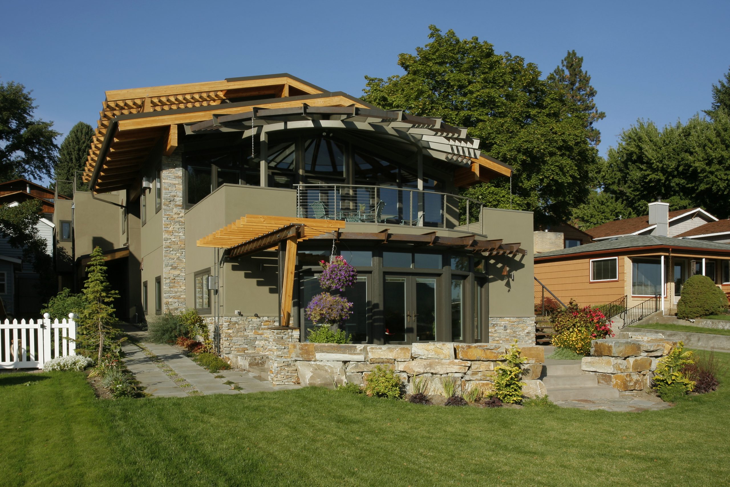 Exterior elevation of the Liberty Lake home with grass, rock, steps, exterior patio covering, veranda and roofline,