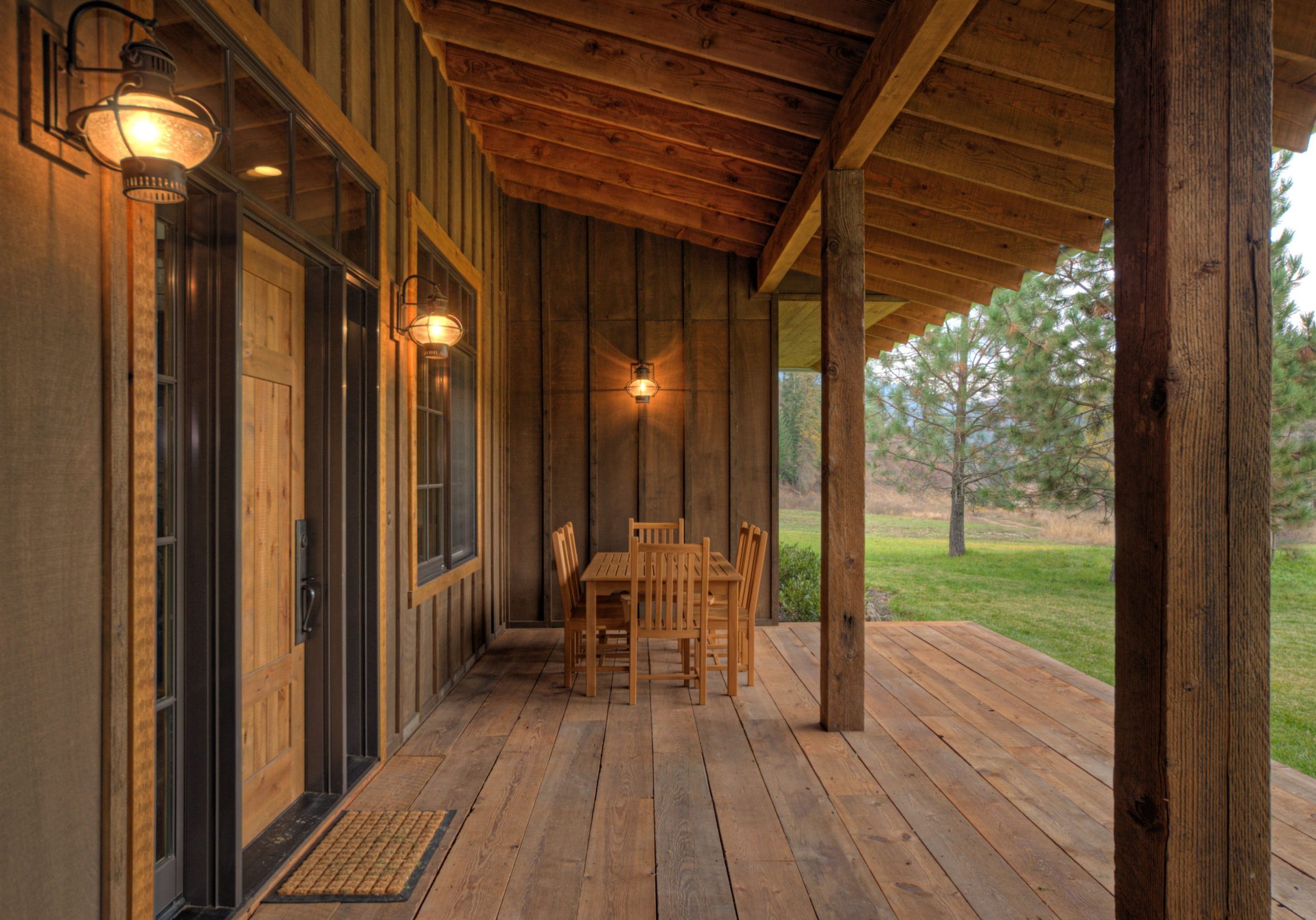 Photo of the Lucky 4 Ranch covered front patio including table with six wood chairs for people to sit on and nature, off to the right.