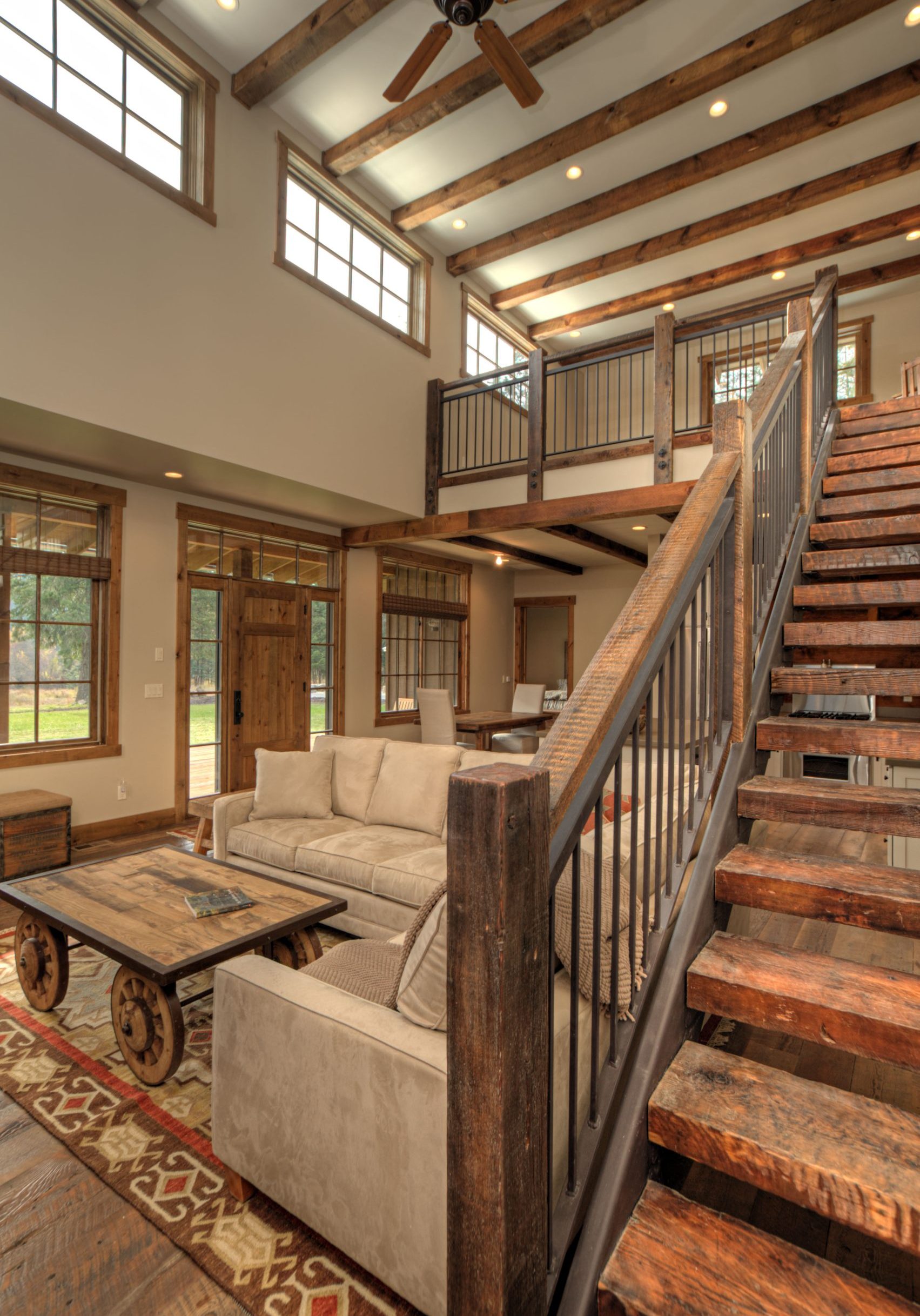 Interior photo of Lucky 4 Ranch. Couch, coffee table, staircase on the right side leading up to the second floor.